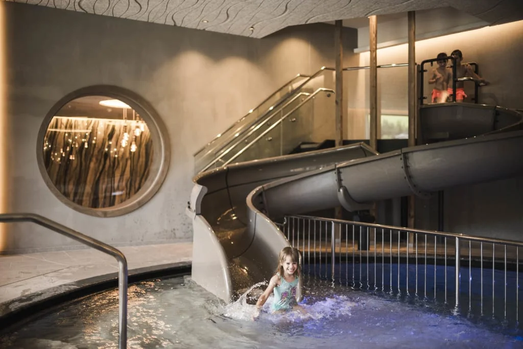 Child playing in indoor pool with slide and water splashes