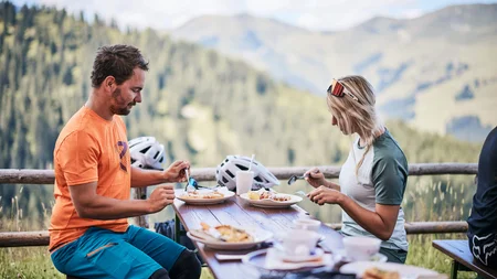 Twee mensen eten buiten met berglandschap op de achtergrond