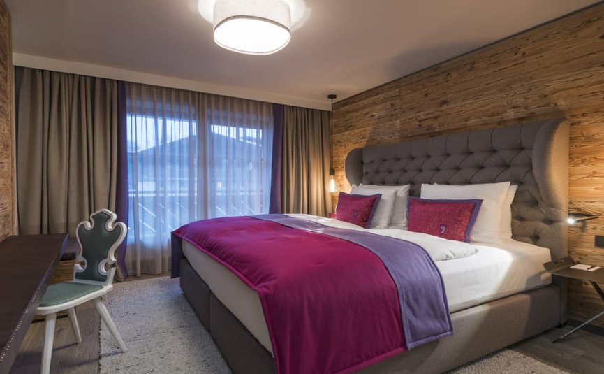 Moderne slaapkamer met houten wand, grijs bed en paars beddengoed