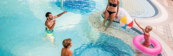 Parent friendly winter days Family with kids playing in pool with mushroom fountain and beach ball