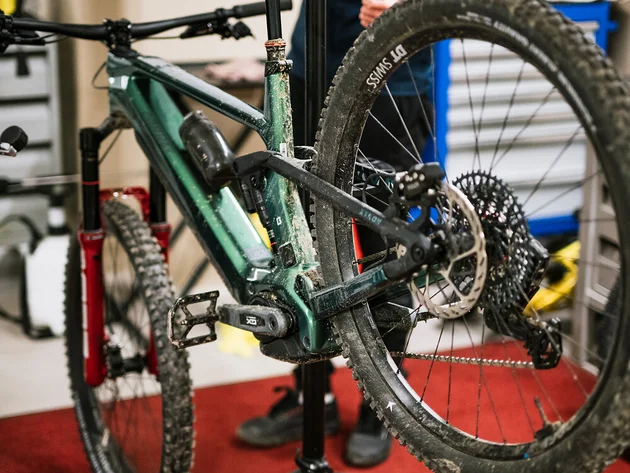 Mountainbike auf Reparaturständer mit Mechaniker im Hintergrund