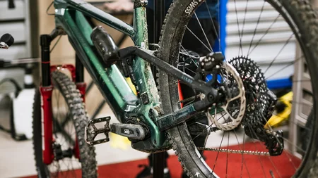 Mountainbike auf Reparaturständer mit Mechaniker im Hintergrund