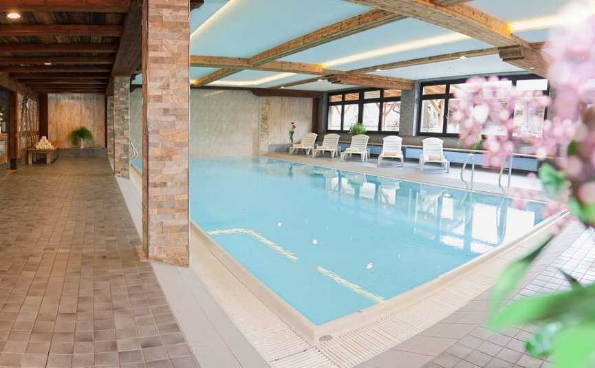 Indoor swimming pool with lounge chairs and wooden ceiling in a spa area