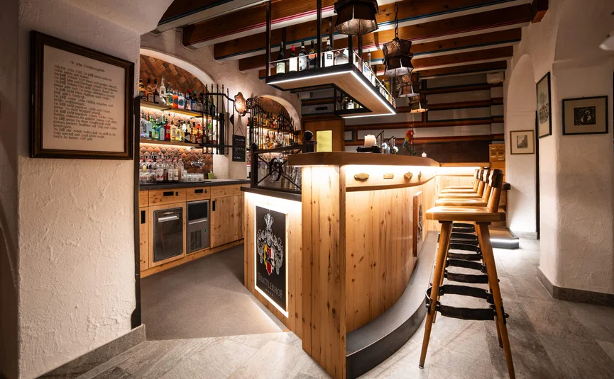 Gemütliche Bar mit Holztheke, Barhockern und Flaschenregalen an der Wand
