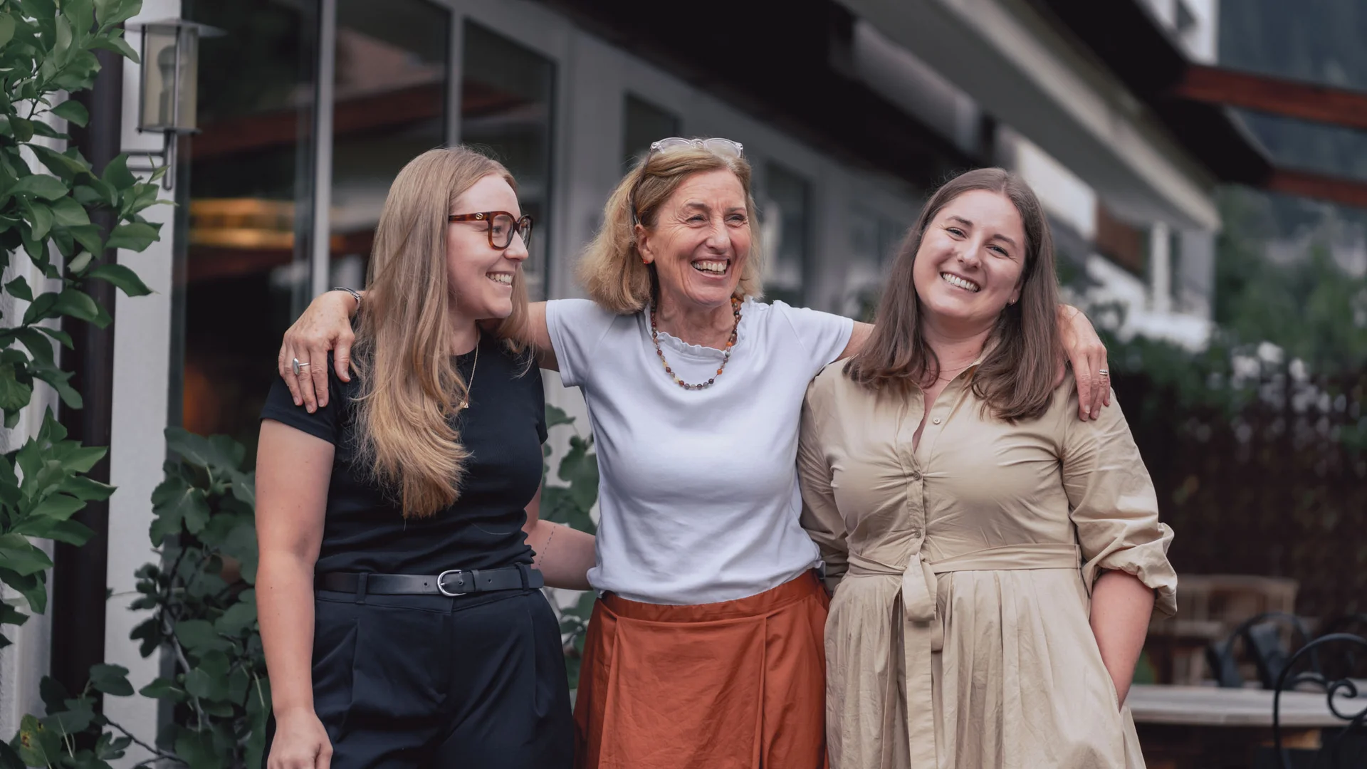 Auf Trail-Mission im Ahrntal © Hotel Innerhofer Drei lachende Frauen stehen draußen Arm in Arm vor einem Gebäude