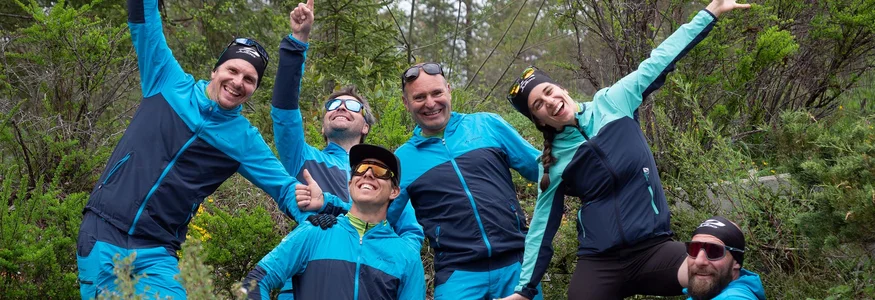 Gruppe von sechs fröhlichen Wanderern in blauer Sportkleidung im Wald