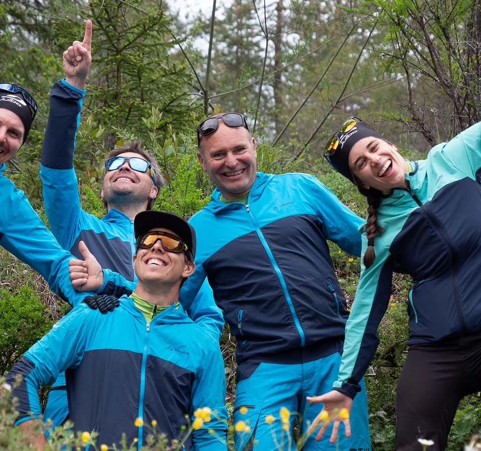 Gruppe von sechs fröhlichen Wanderern in blauer Sportkleidung im Wald