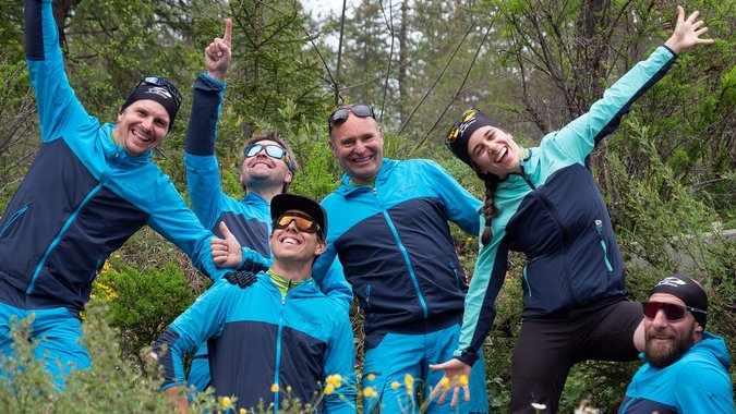 Gruppe von sechs fröhlichen Wanderern in blauer Sportkleidung im Wald