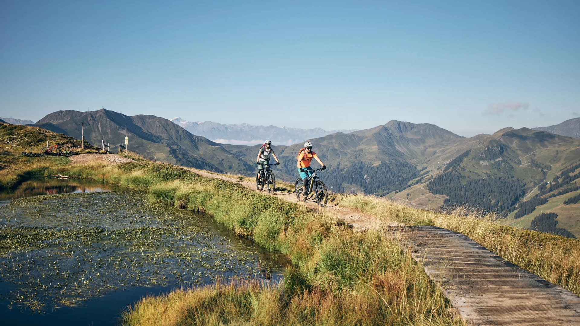 Touren & Trails © Tobias Köhler Zwei Mountainbiker auf Bergweg mit Berglandschaft im Hintergrund