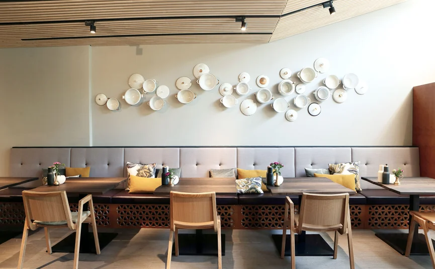 Modern eingerichteter Sitzbereich mit Tischen, Stühlen und Wanddekoration aus Tellern.
