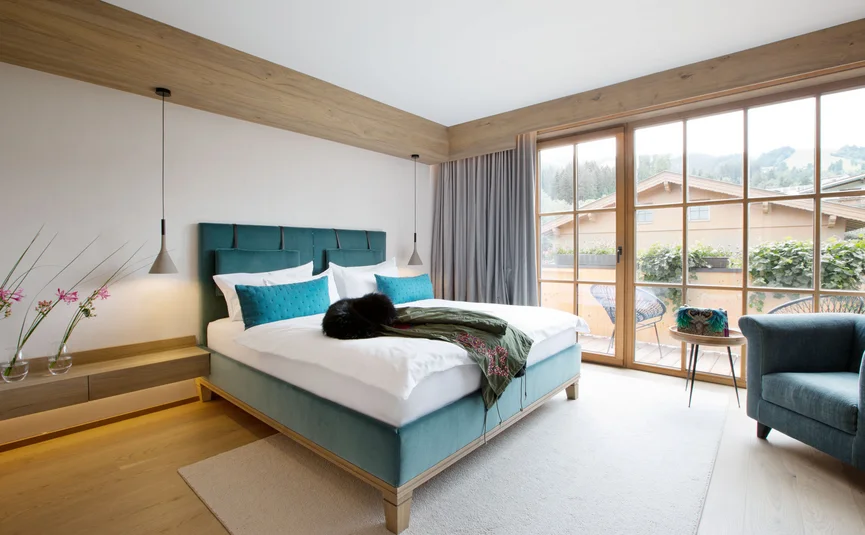 Modernes Schlafzimmer mit großem Bett, Holzdecke und Fenster mit Bergblick
