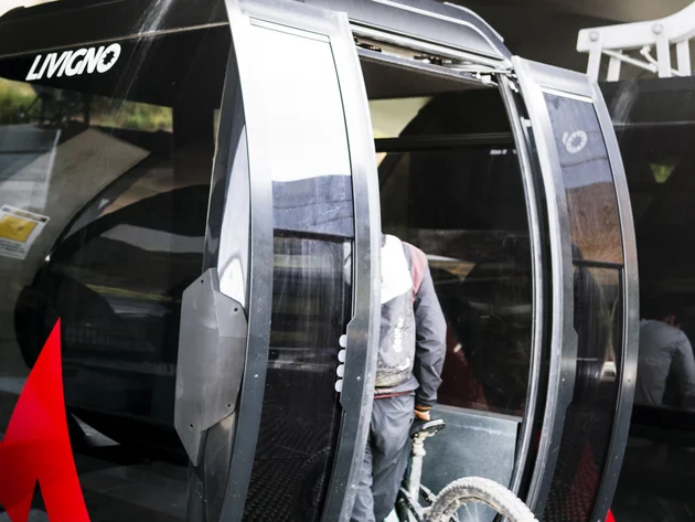Person schiebt Mountainbike in eine Gondel der Seilbahn Livigno