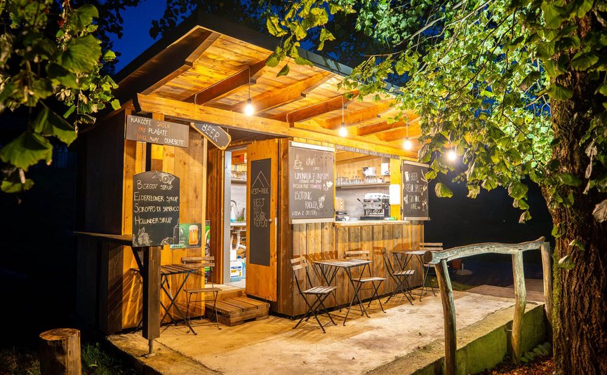 Lit wooden food stand with tables and chairs at night