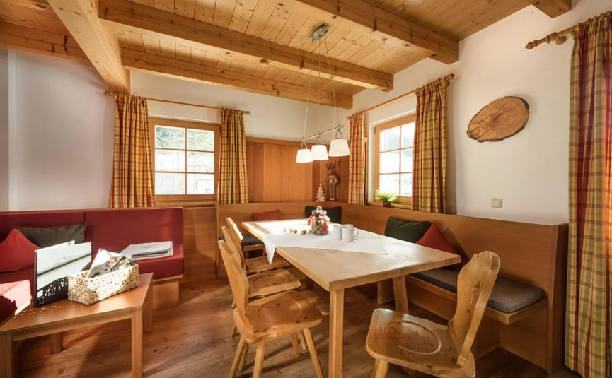Gemütlicher Essbereich mit Holztisch, Stühlen und roten Kissen