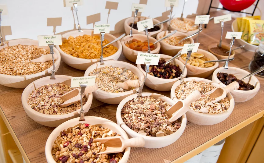 Various muesli types and dried fruits in wooden bowls with scoops