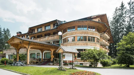 Was steckt hinter dem Umweltengagement von Bikehotels? © Epidos doo Großes Hotelgebäude aus Holz mit überdachtem Eingang und Fahrrädern davor