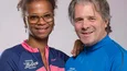 Zwei Personen in bunten Mountainbike-Shirts lächelnd vor grauem Hintergrund