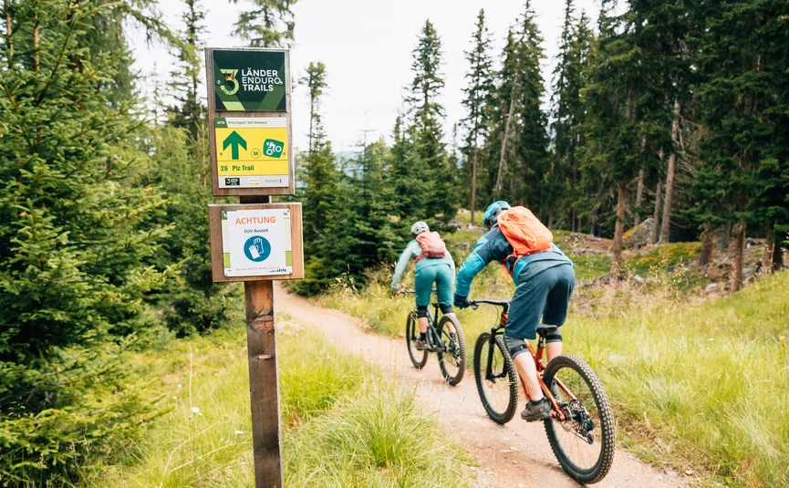 Twee mountainbikers fietsen op de 26 Piz Trail door het bos