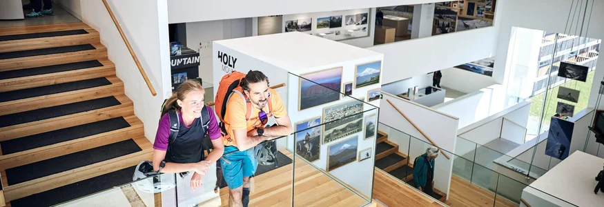 Besucher in moderner Galerie mit Fotos und Treppen