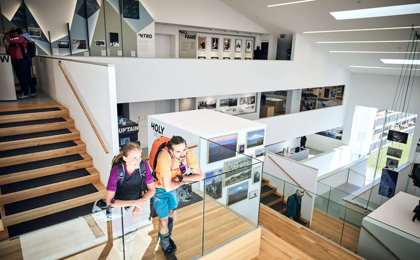 Besucher in moderner Galerie mit Fotos und Treppen