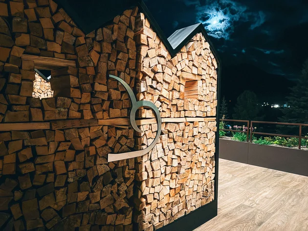 Hauswand aus Holzscheiten bei Nacht mit Mond und Wolken