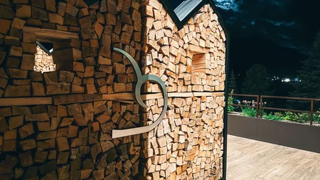 Hauswand aus Holzscheiten bei Nacht mit Mond und Wolken
