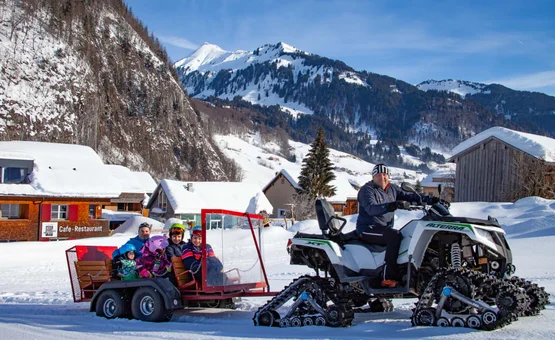 Snowmobile pulling trailer with children in snowy mountain village