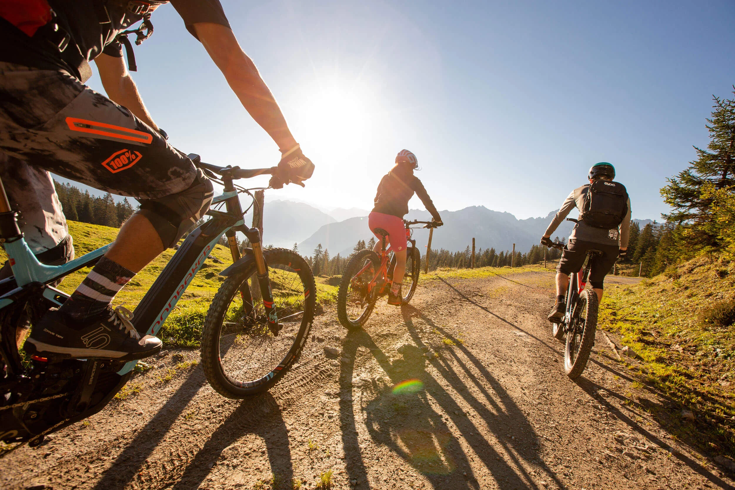 Best of Brandnertal © Michael Marte - Bikepark Brandnertal Drei Mountainbiker fahren auf einem sonnigen Bergweg mit Bergen im Hintergrund