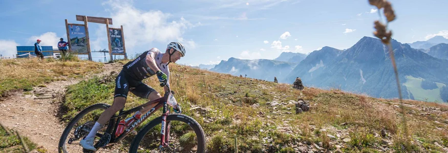 Kronplatz King Marathon – The King of the Dolomites Mountainbiker fährt bergab auf einem Pfad bei sonnigem Wetter mit Bergen im Hintergrund