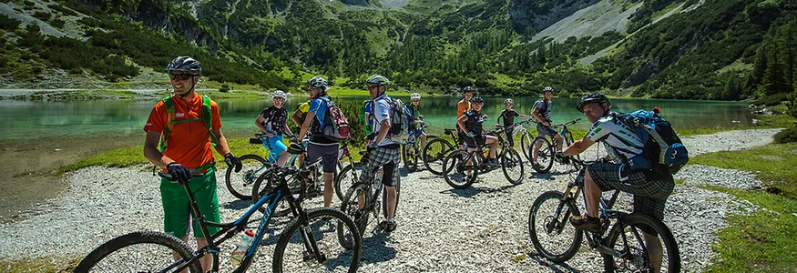 Group of cyclists by mountain lake with rocky peaks in background