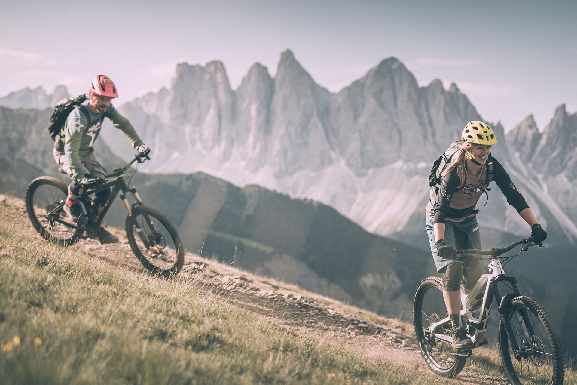 Zwei Radfahrer fahren auf Bergpfad mit Bergen im Hintergrund
