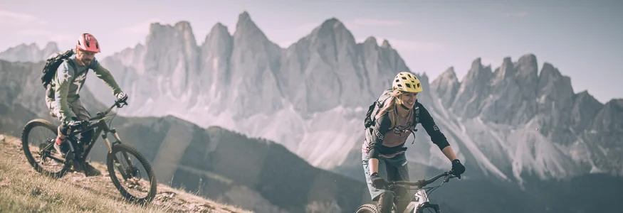 Zwei Radfahrer fahren auf Bergpfad mit Bergen im Hintergrund