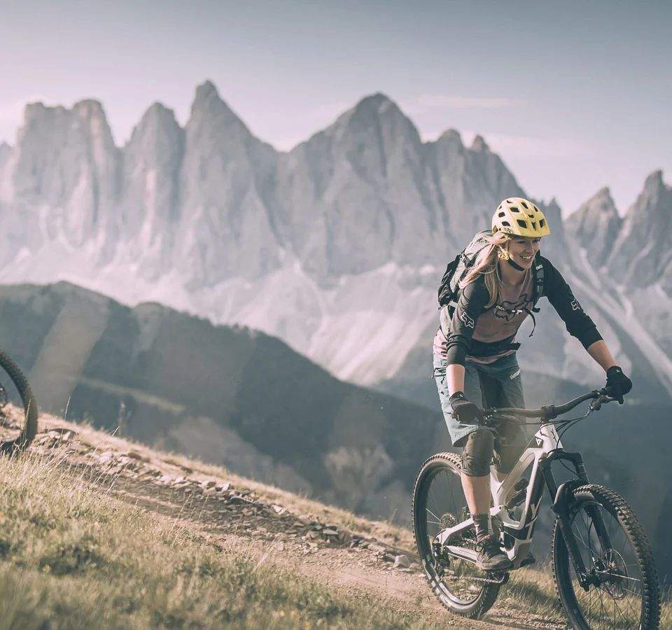 Zwei Radfahrer fahren auf Bergpfad mit Bergen im Hintergrund
