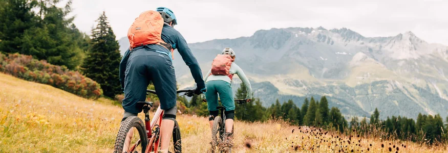Zwei Mountainbiker fahren auf einem Weg durch ein bergiges Grasland