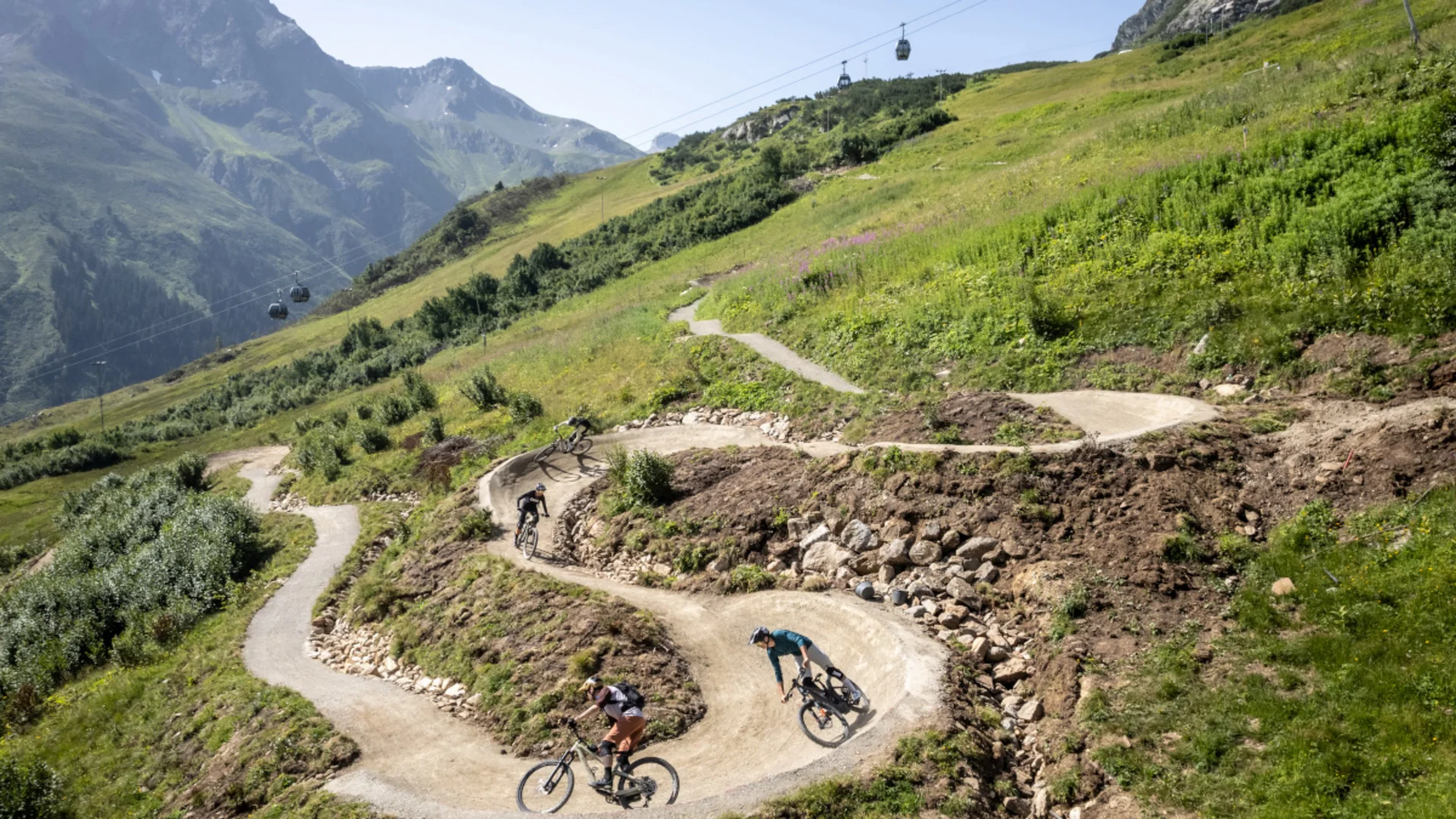 Mountainbiker fahren einen kurvigen Weg in den Alpen hinab