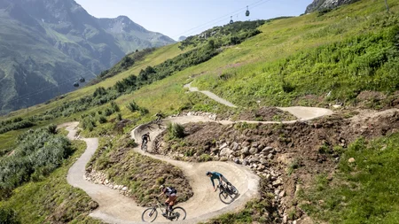 Mountainbiker fahren einen kurvigen Weg in den Alpen hinab