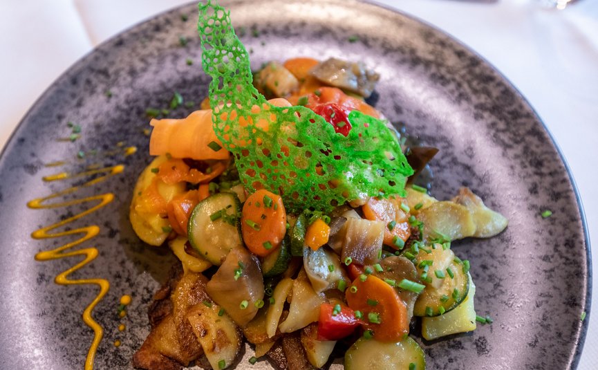 Colorful vegetable dish with green edible decoration on gray plate