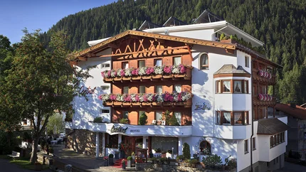 Hotel met bloemenversierde balkons voor beboste bergachtergrond