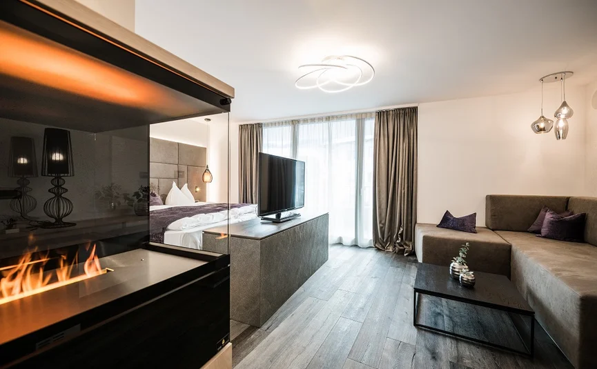 Modern living room with fireplace, sofa, TV, and large window with curtains.