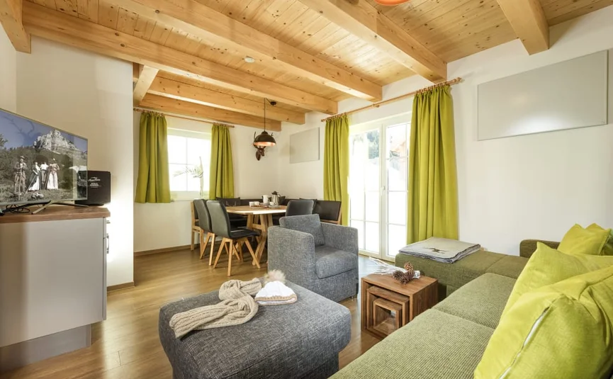 Modernes Wohnzimmer mit grünem Sofa, Holzdecke und Esstisch mit schwarzen Stühlen