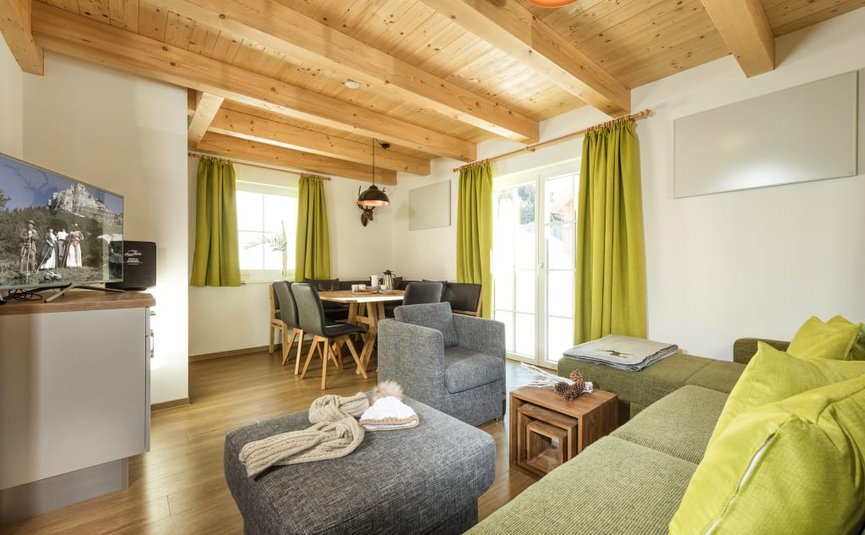 ACTIVE BIKE package stays 3 nights for 2-6 persons Modern living room with green sofa, wooden ceiling, and dining table with black chairs