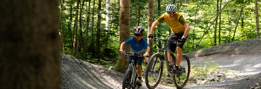 Kind en volwassene mountainbiken op bosweg