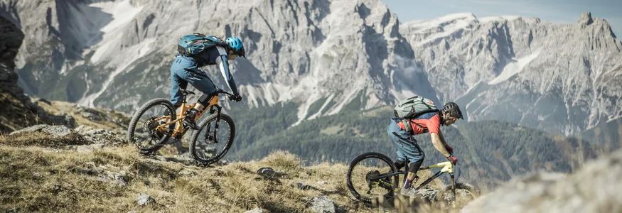 Twee mountainbikers dalen af in de Alpen bij helder weer