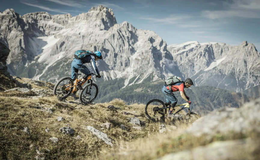 Twee mountainbikers dalen af in de Alpen bij helder weer