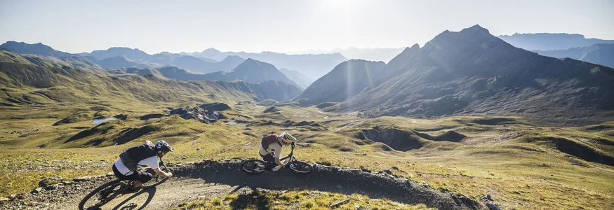 Zwei Mountainbiker fahren auf einem Bergpfad bei sonnigem Wetter