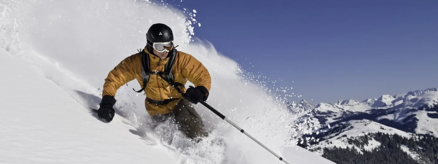 Schnee(s)pass 2-4+3 Skiër glijdt door diepe poedersneeuw met bergen op de achtergrond