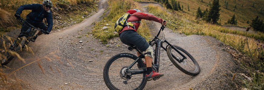 Zwei Mountainbiker fahren auf einem kurvigen Bergweg