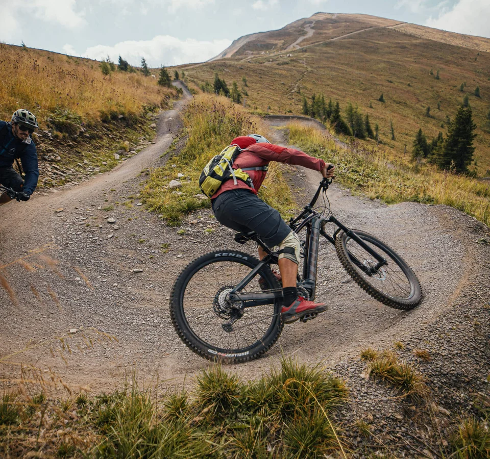 Zwei Mountainbiker fahren auf einem kurvigen Bergweg