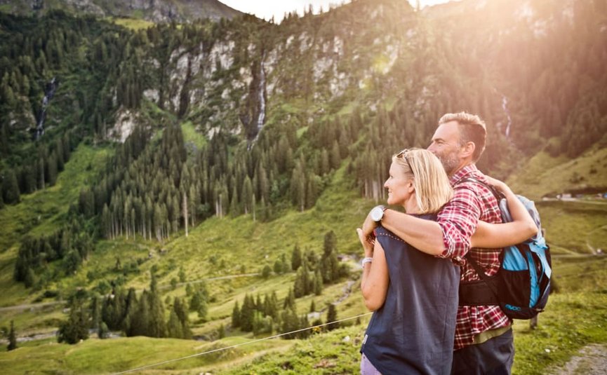 SUMMER IN THE MOUNTAINS Couple hugging while hiking in sunny mountain landscape