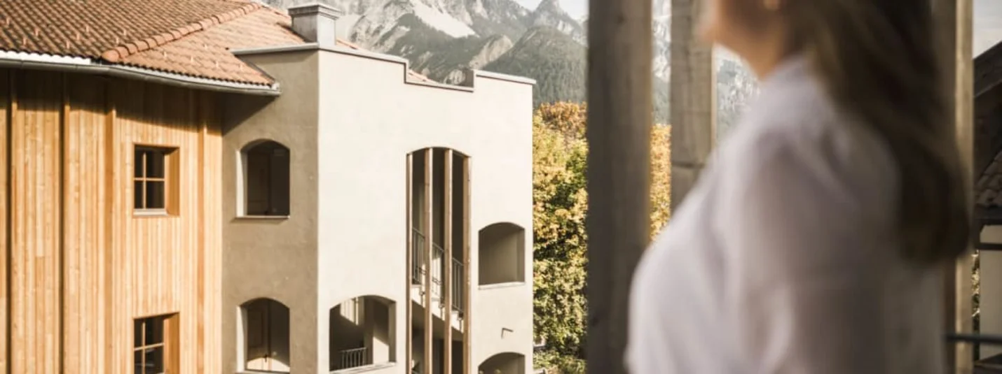 Woman looking from balcony at mountains and buildings in sunlight